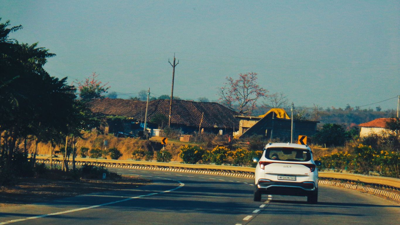 a white car driving down a road next to a forest