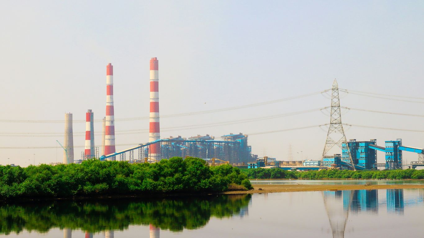 a factory is seen in the background of a body of water