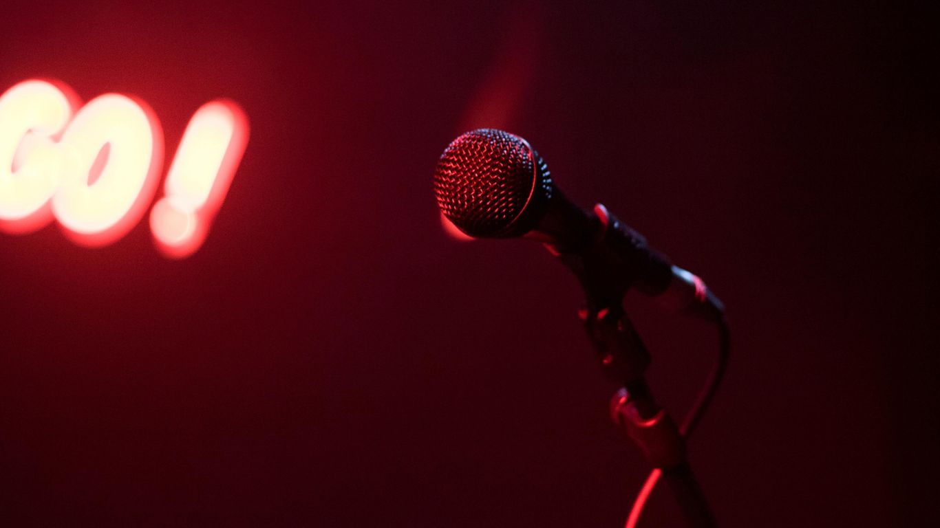 A microphone in front of a soft red background, illuminated.