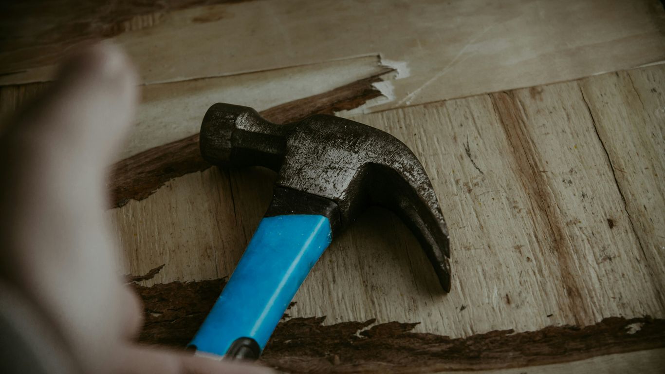 a hammer with a blue handle on a piece of wood