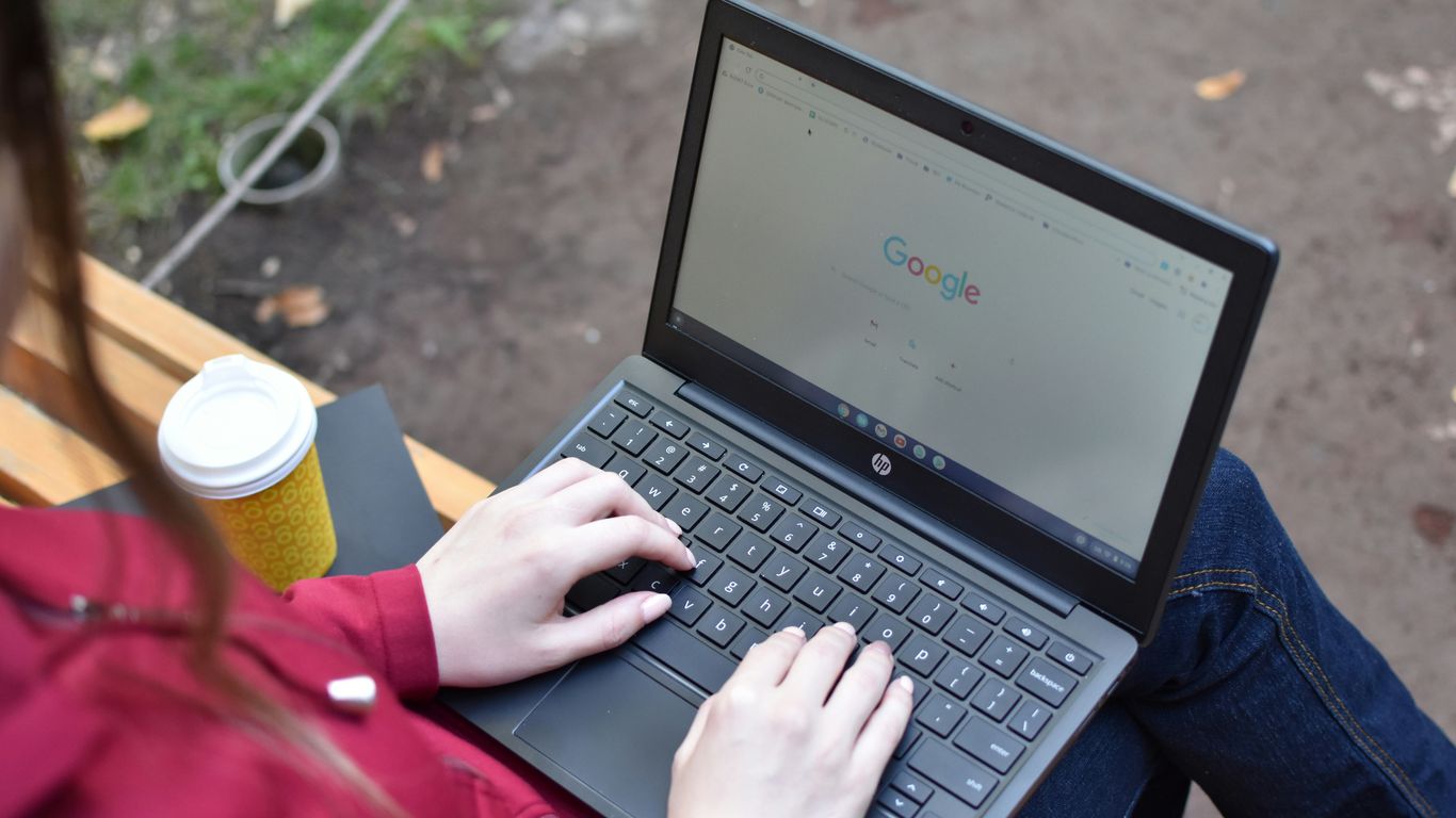 a woman sitting on a bench using a laptop computer