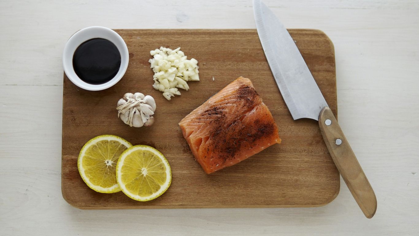 gray knife and orange flesh meat on wooden chopping board