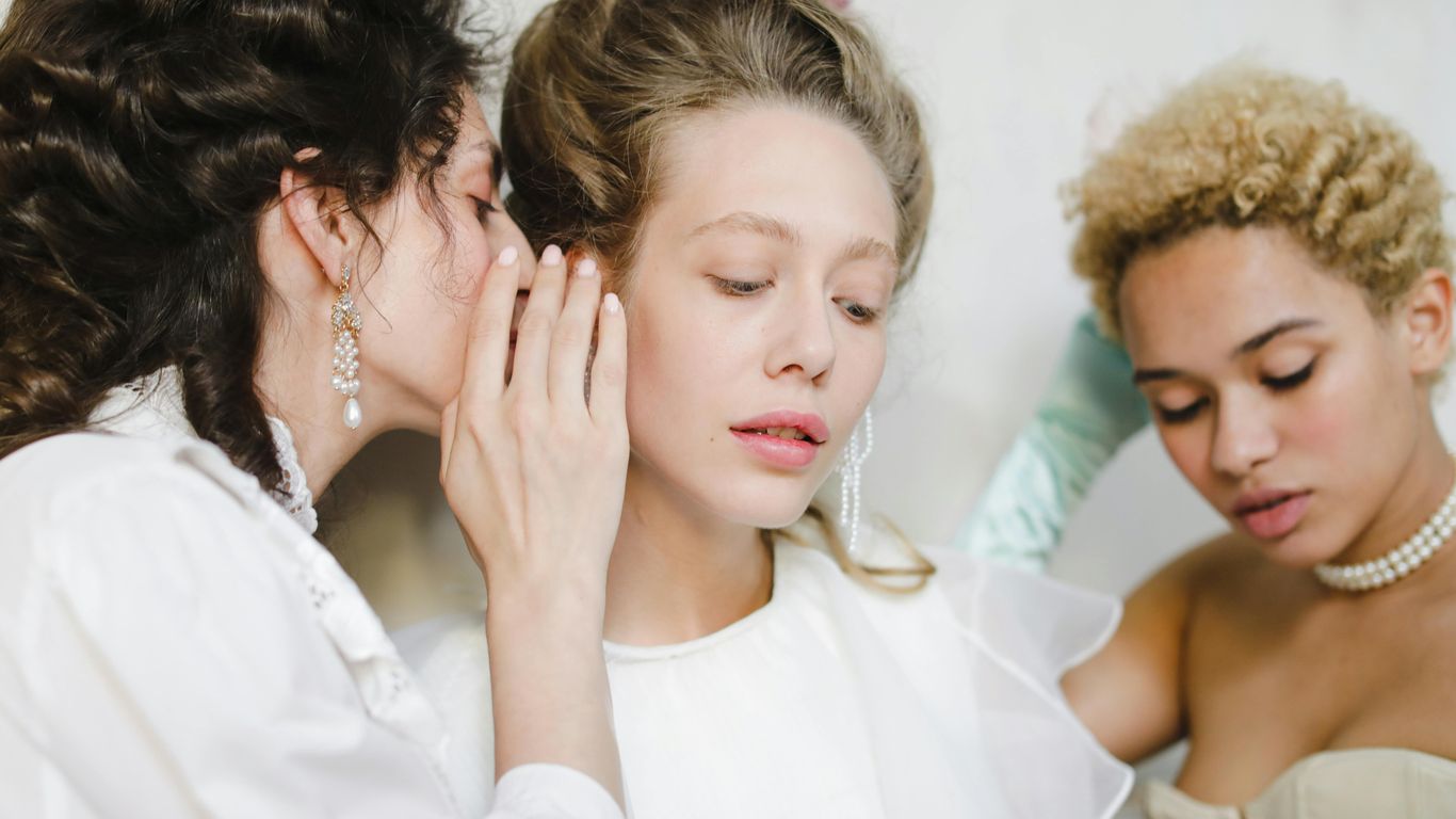 Three women in historical attire sharing secrets.