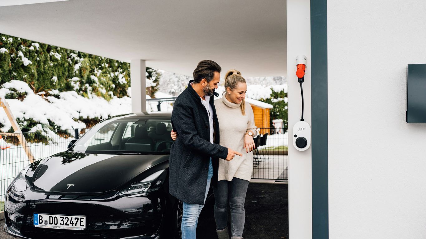 Couple by their electric car next to a charger.