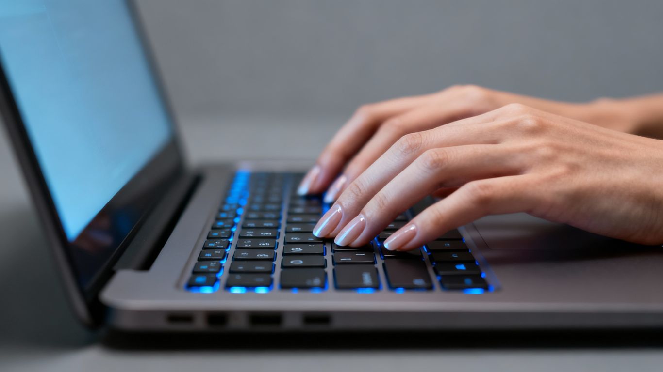 Hands typing on a laptop keyboard.