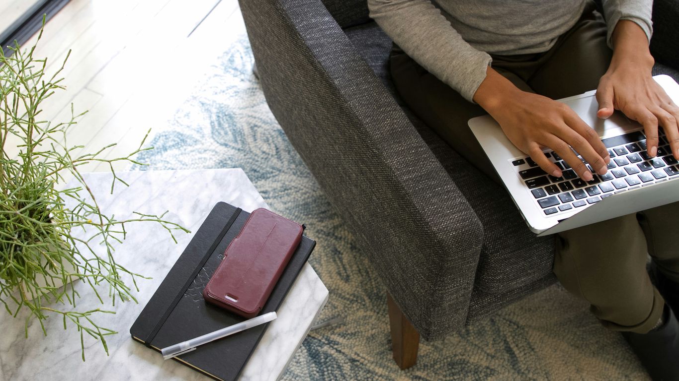 a woman sitting on a couch using a laptop computer