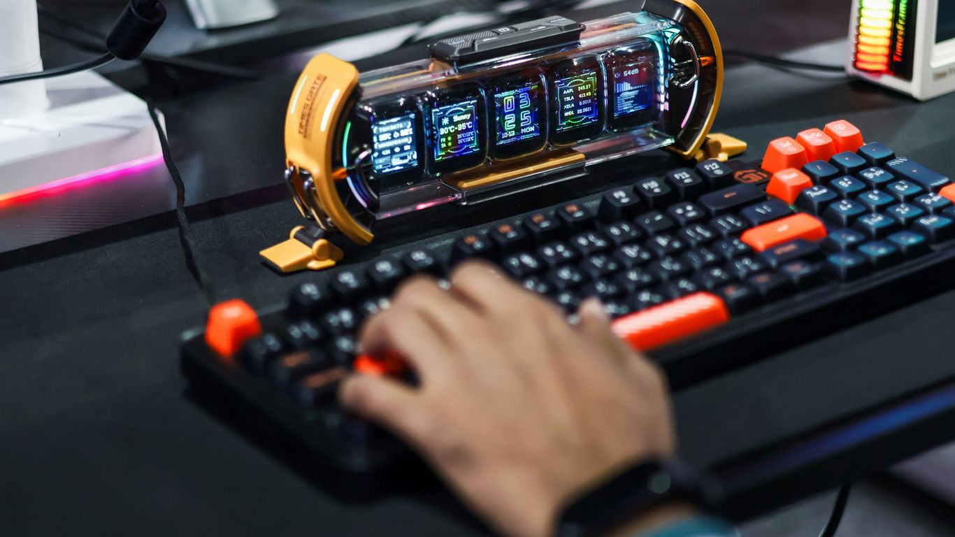 Gamer typing on a futuristic keyboard with multiple screens.