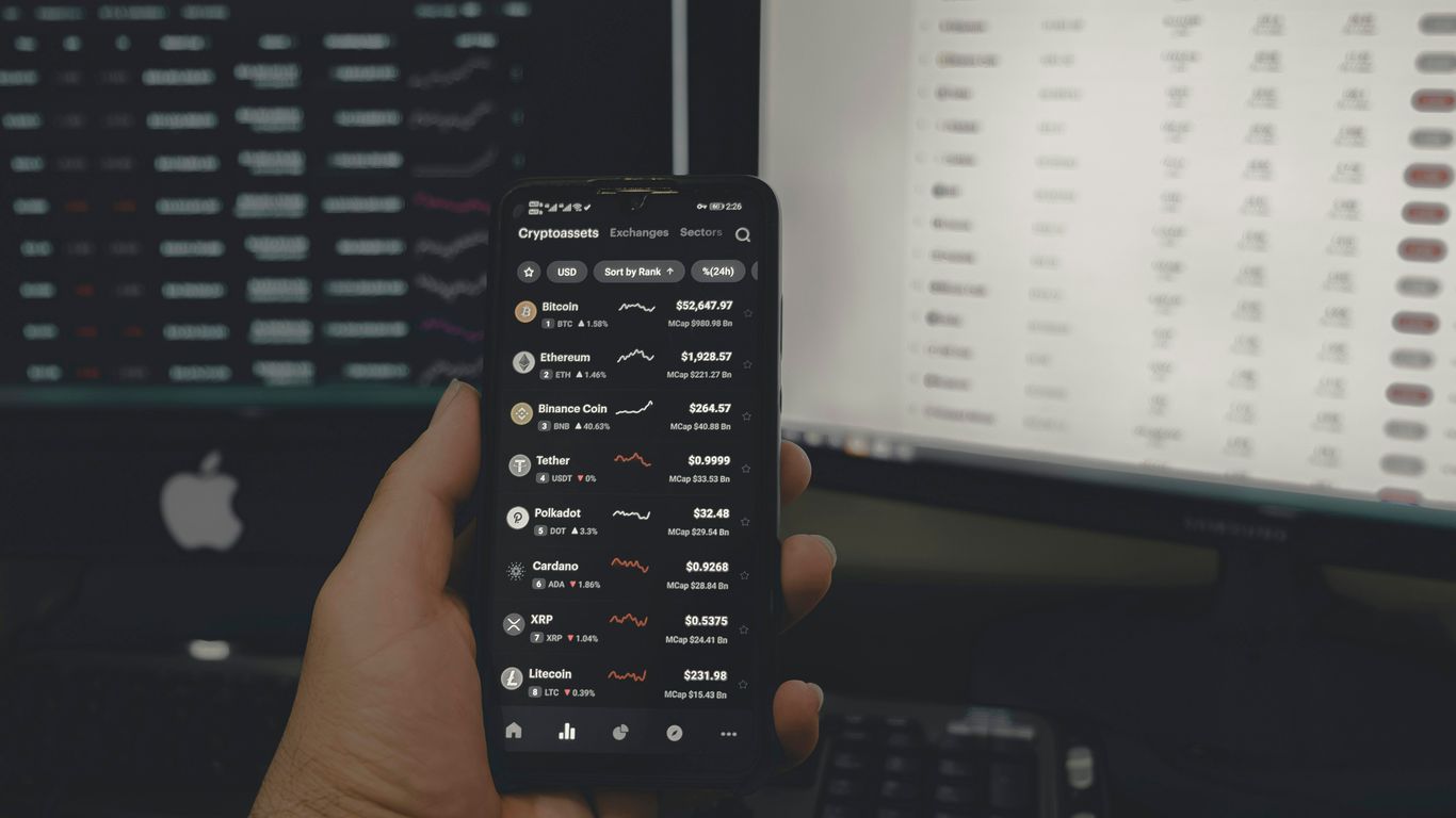 A hand holding a smartphone displaying cryptocurrency information and exchange rates.