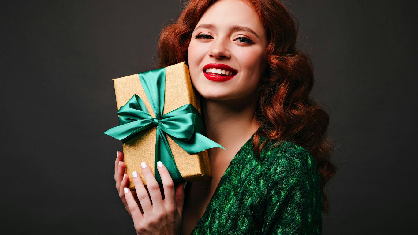 a woman holding a present box with a green bow