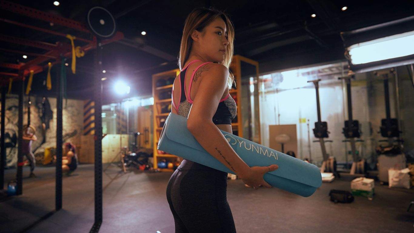 woman holding blue exercise mat