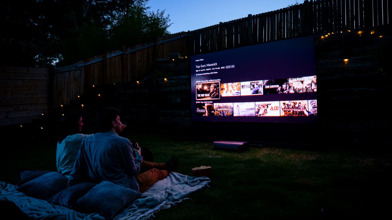 Two people sitting on a blanket watching a movie