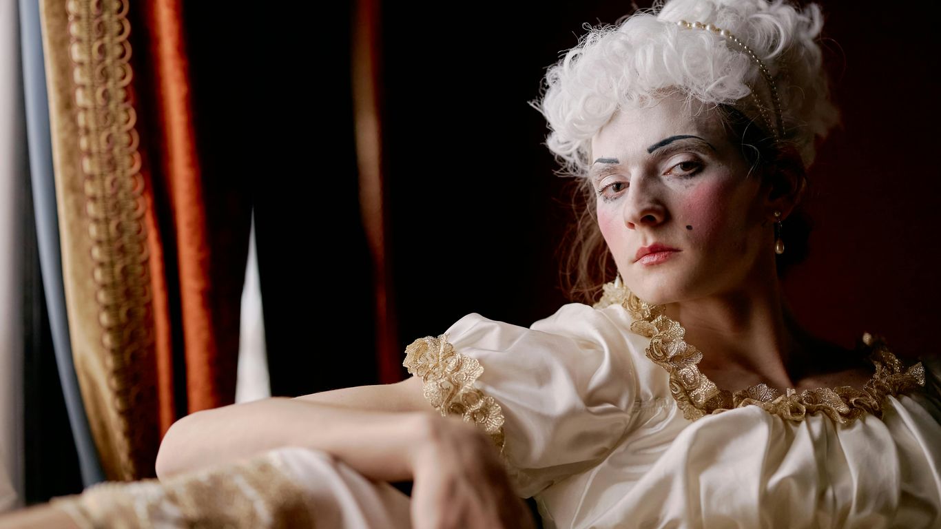 Person in historical costume with white wig and dramatic makeup.