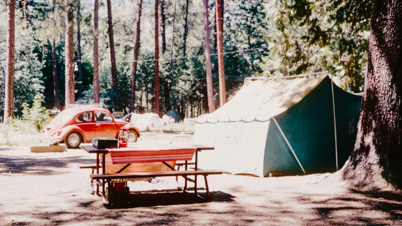 A car parked next to a tent in the woods