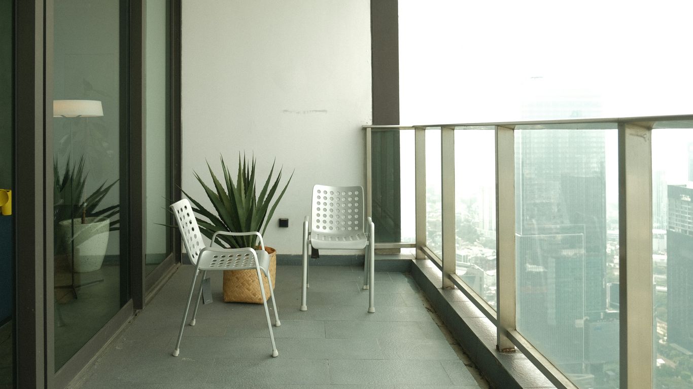 Balcony with chairs, plants, and a city view.