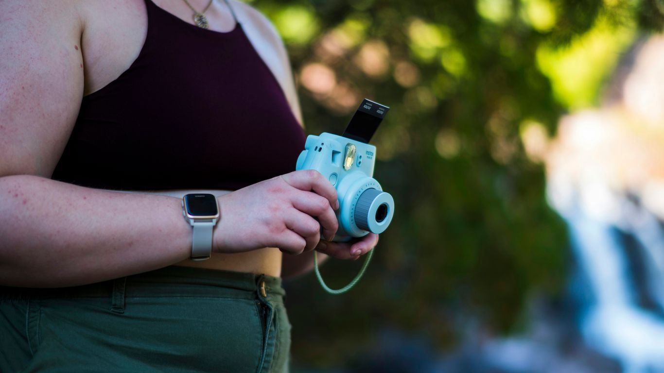 a woman in a tank top holding a camera