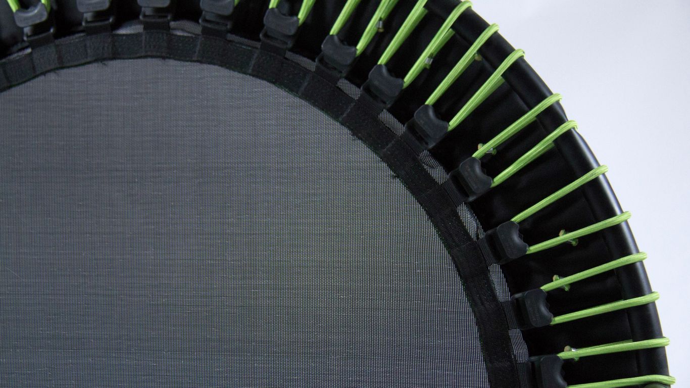 Close-up of a trampoline with green elastic bands, black frame.