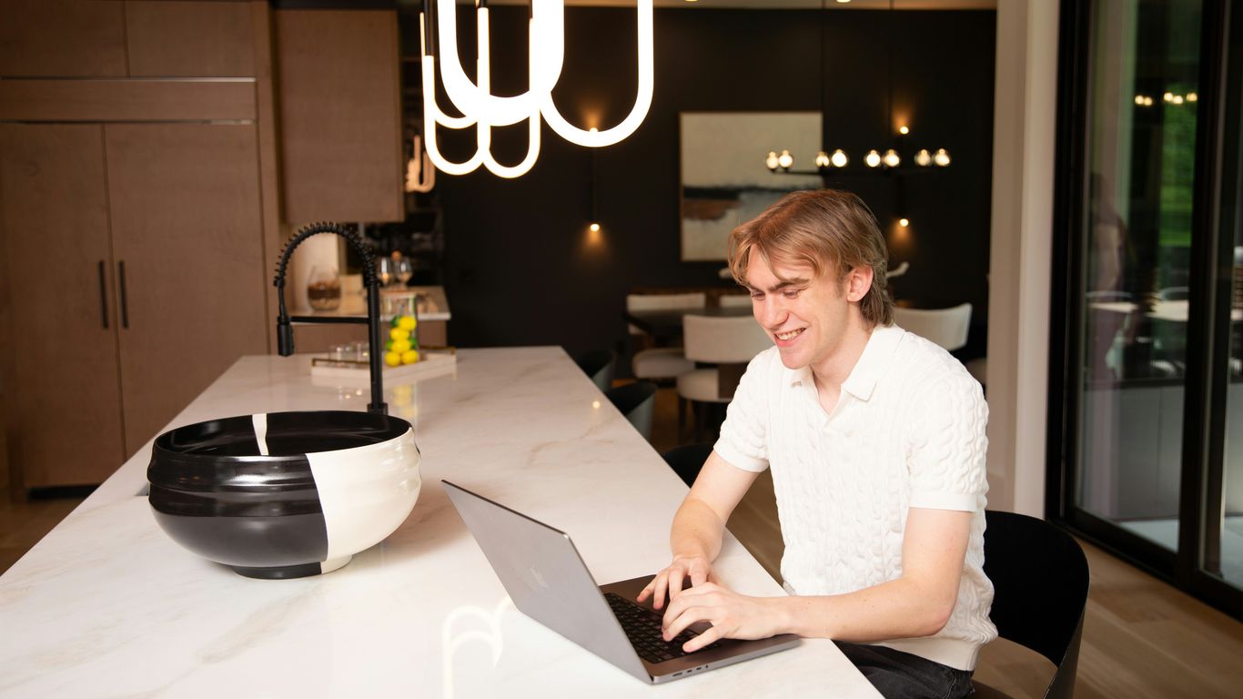 A man works on a laptop in a modern kitchen.