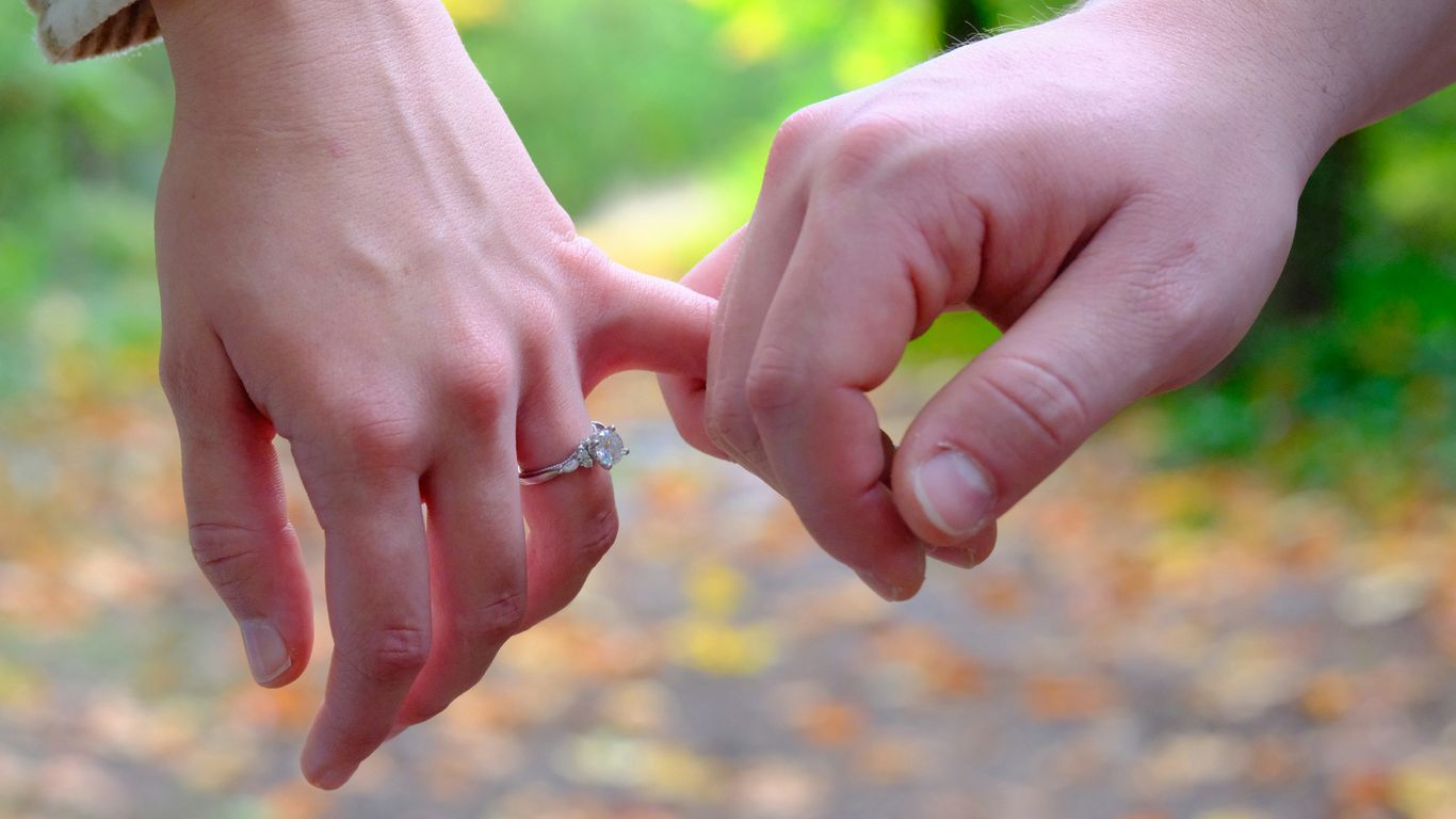 Two hands interlock fingers in a promise gesture of commitment.