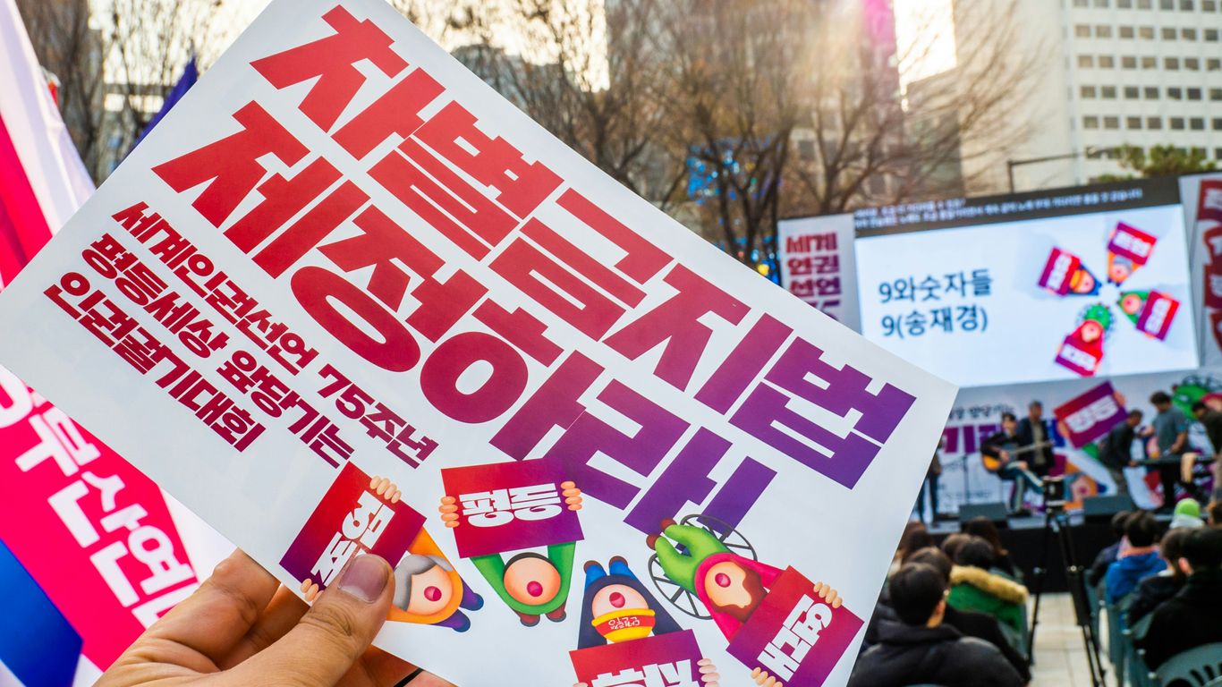A person holding up a sign in front of a crowd