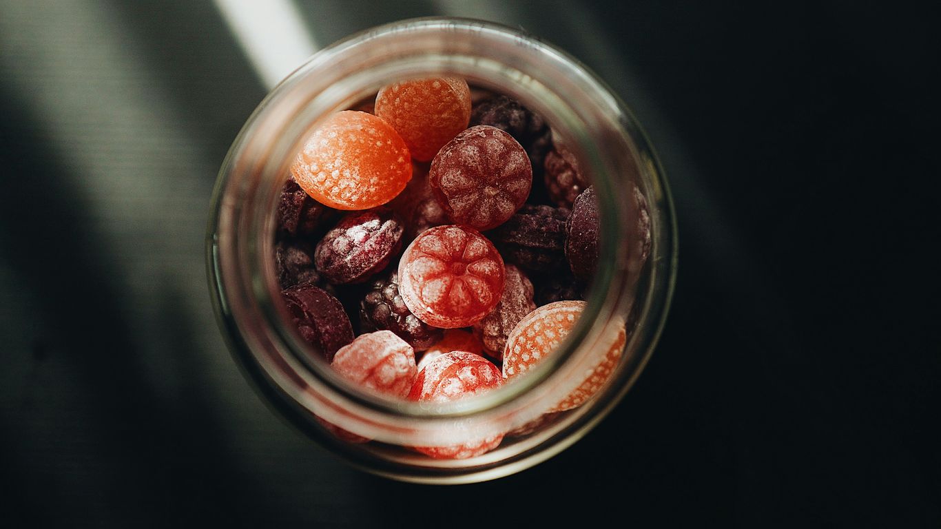 A glass jar filled with raspberries and oranges
