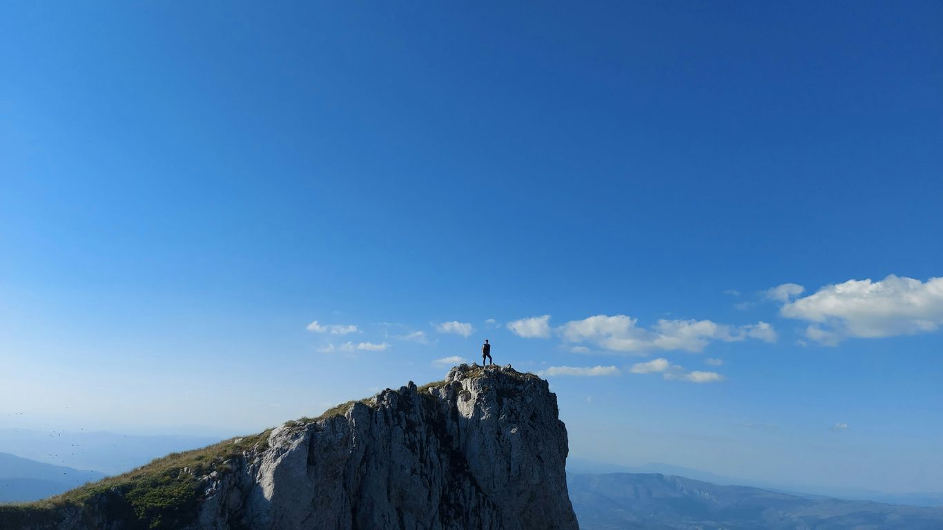 person standing on rock formation under blue sky during daytime