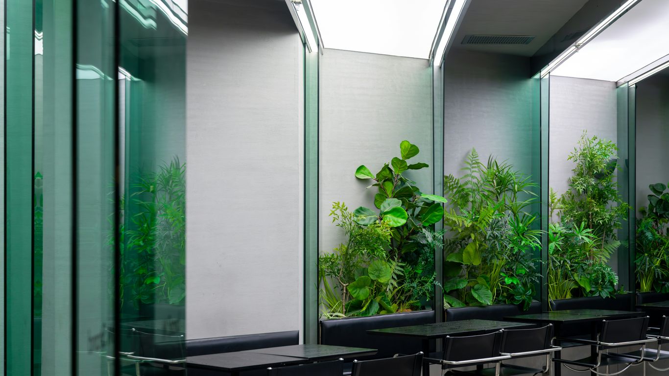 Modern office interior with plants and seating areas for tables.