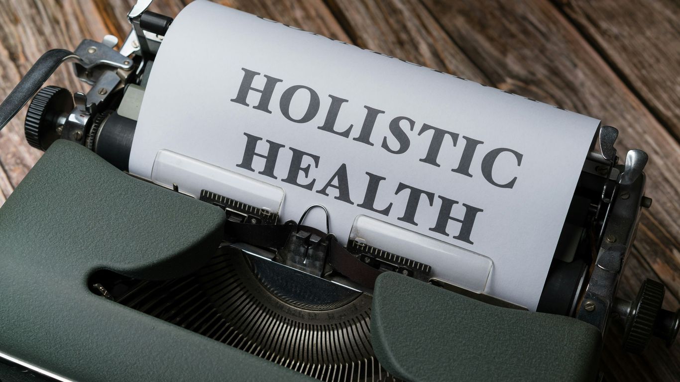 a close up of a typewriter with a paper that says holstic health