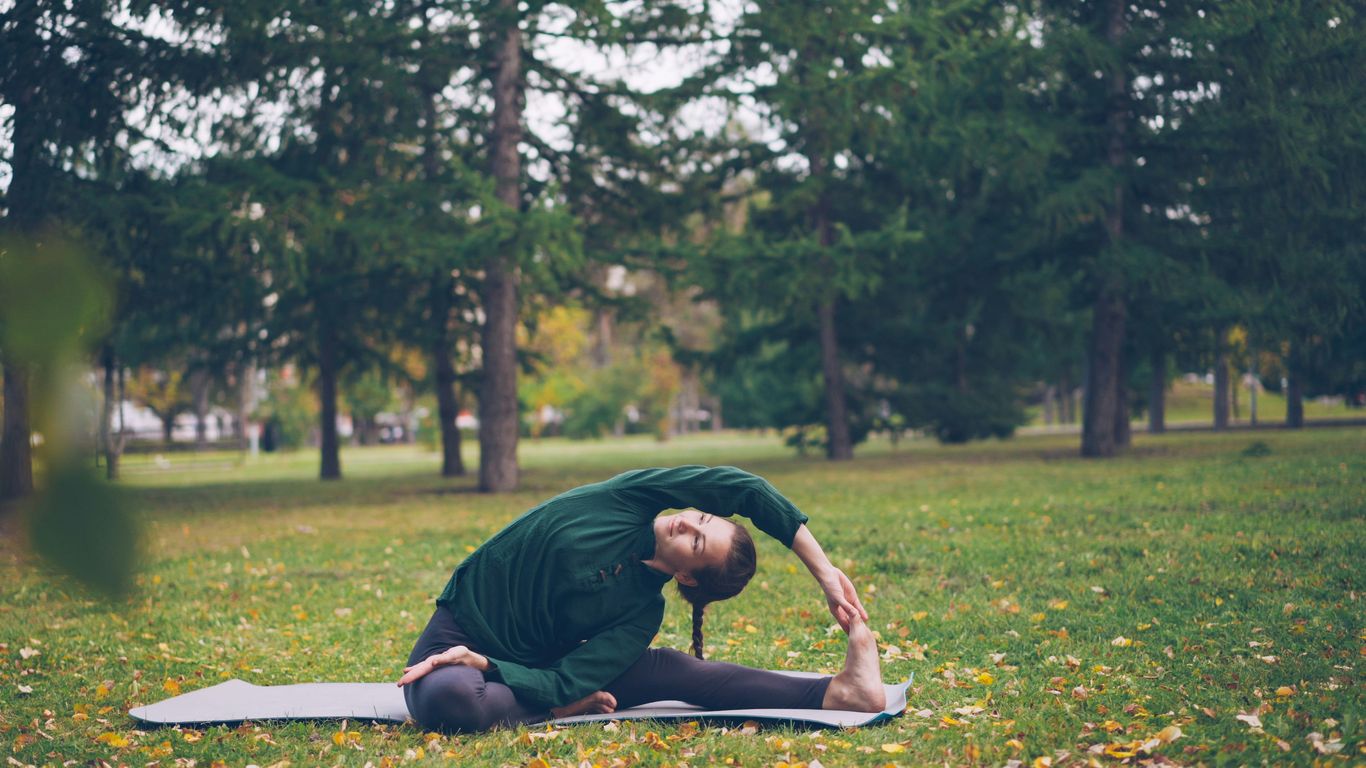 Woman stretching on yoga mat in park