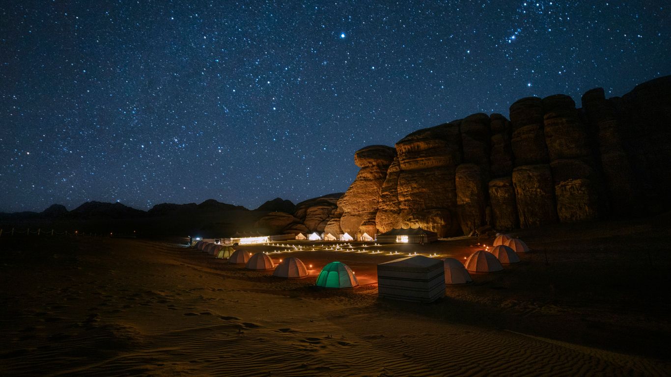 A tent set up in the middle of a desert at night