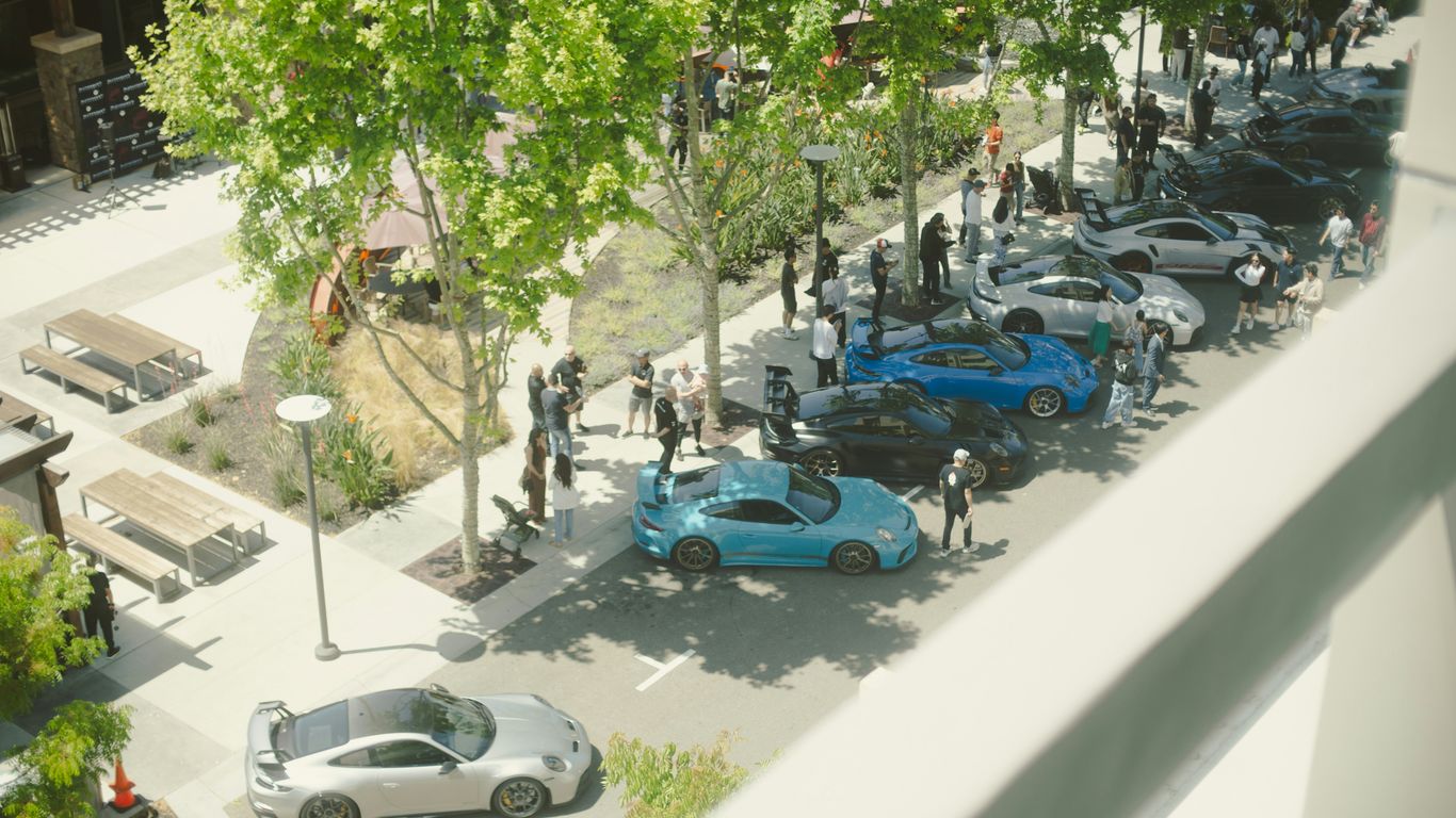 Cars are parked amongst people in a parking lot.
