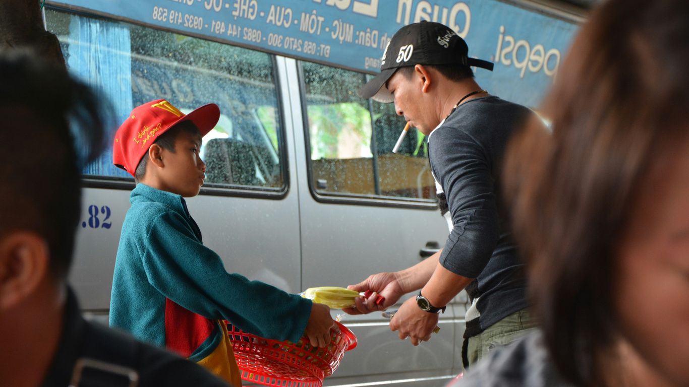 man in blue shirt and black cap holding red plastic bag