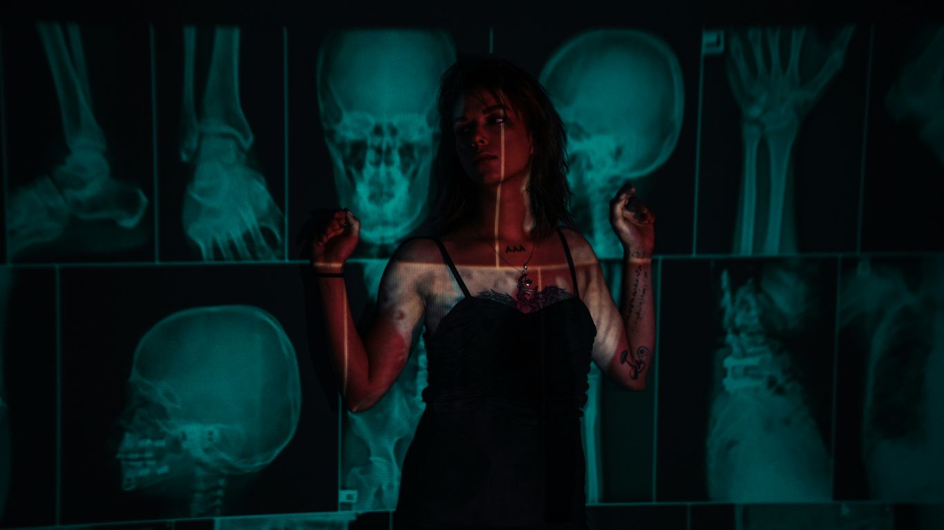 Woman stands before x-rays with a red overlay.