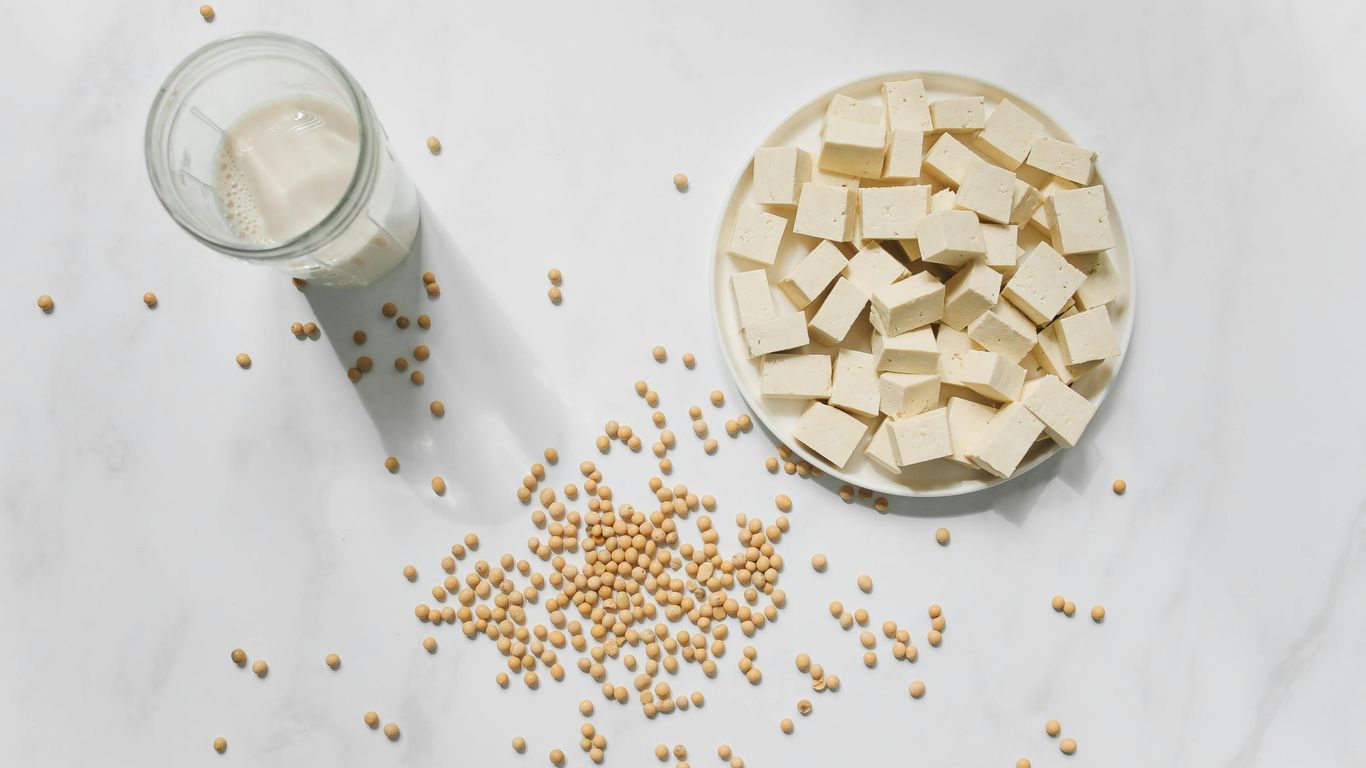 Tofu cubes, soybeans, and a glass of soy milk displayed.