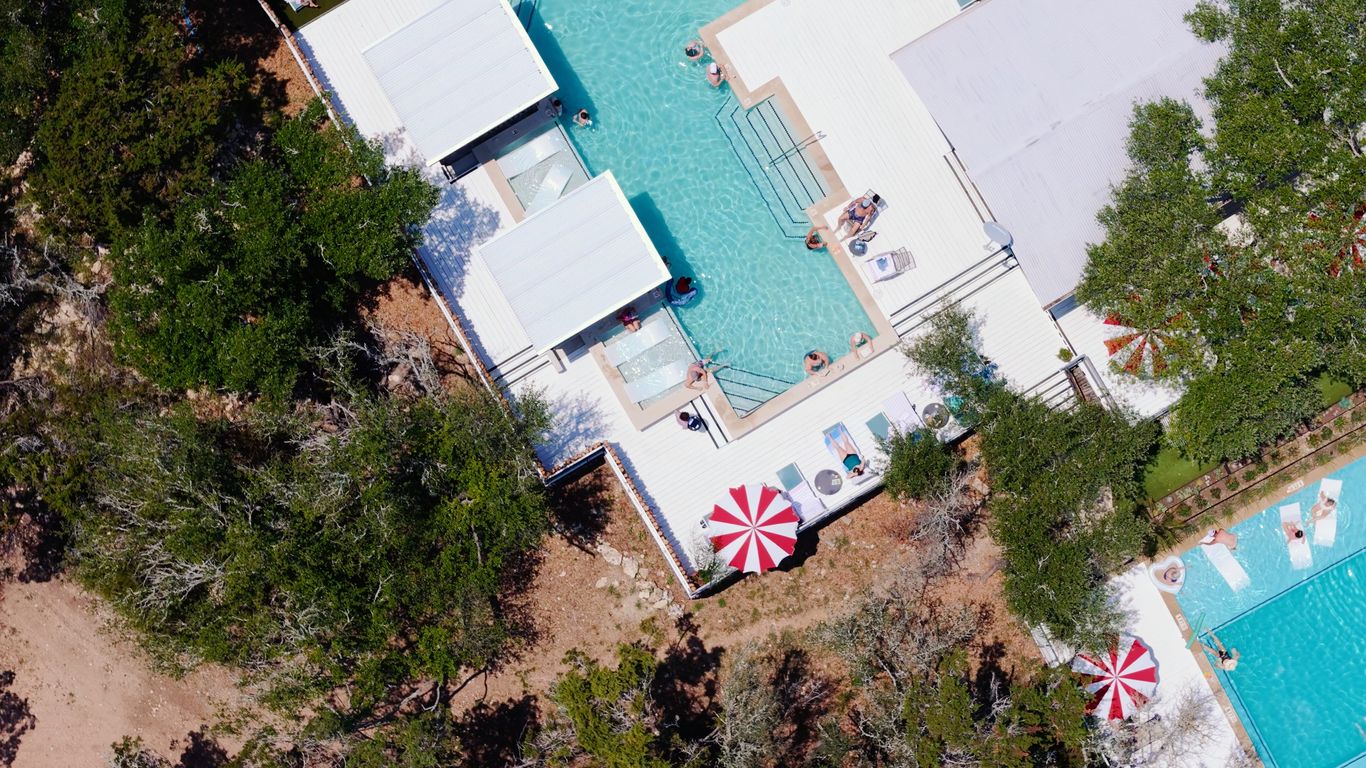 Aerial view of a resort with pools, lounge chairs, and trees.