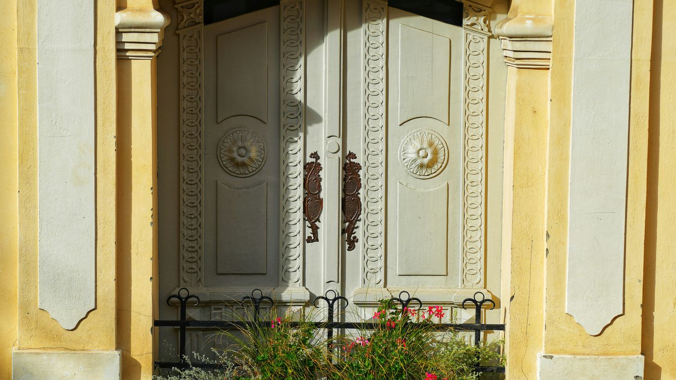a building with a large white door and a flower bed in front of it