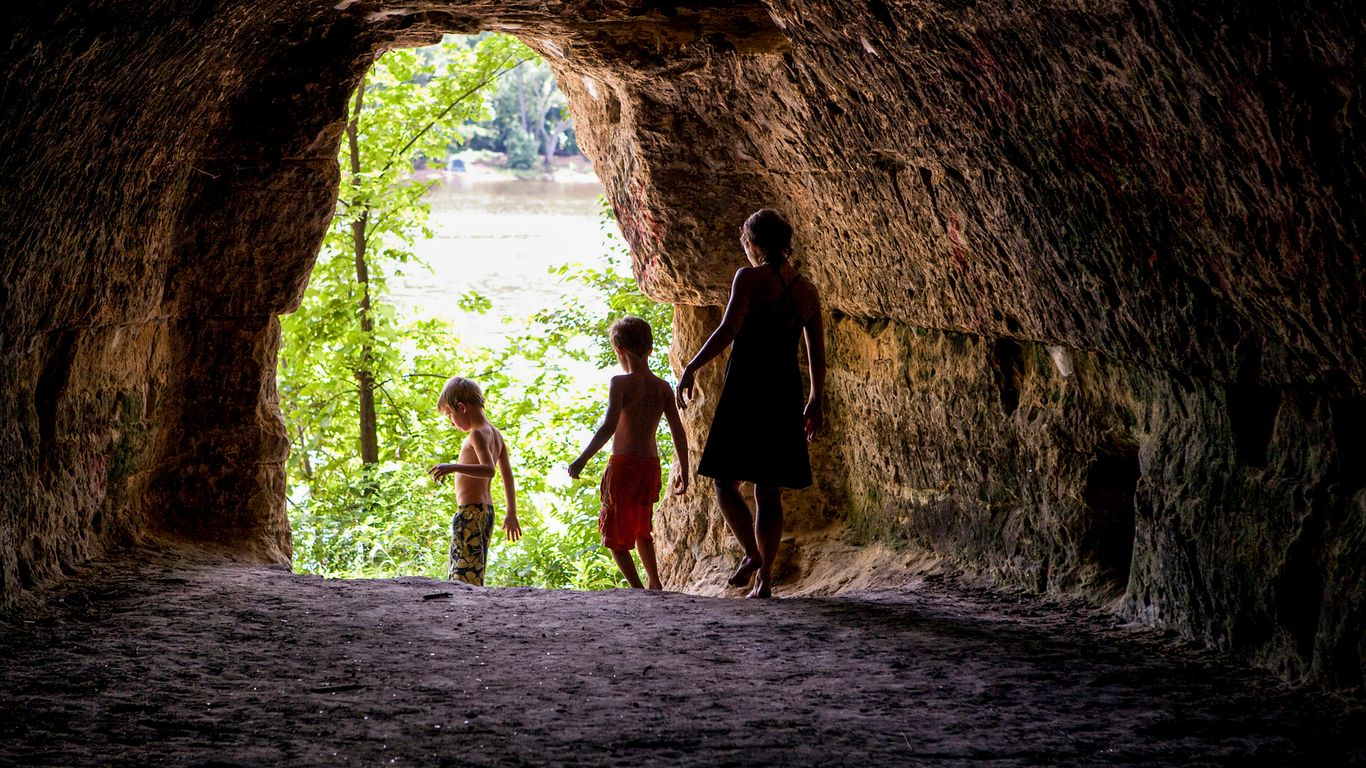 2 women in black dress walking on brown tunnel during daytime
