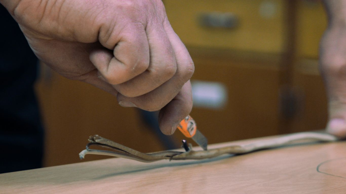 a man is cutting a piece of wood with a pair of scissors