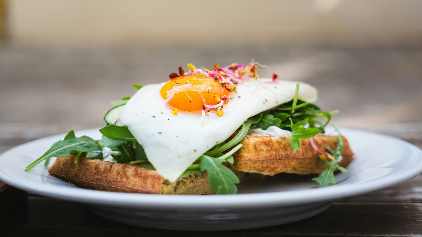 A white plate topped with an egg and greens