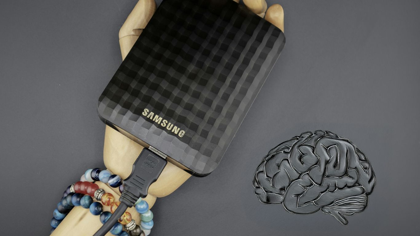 A hand holding a cell phone next to a brain