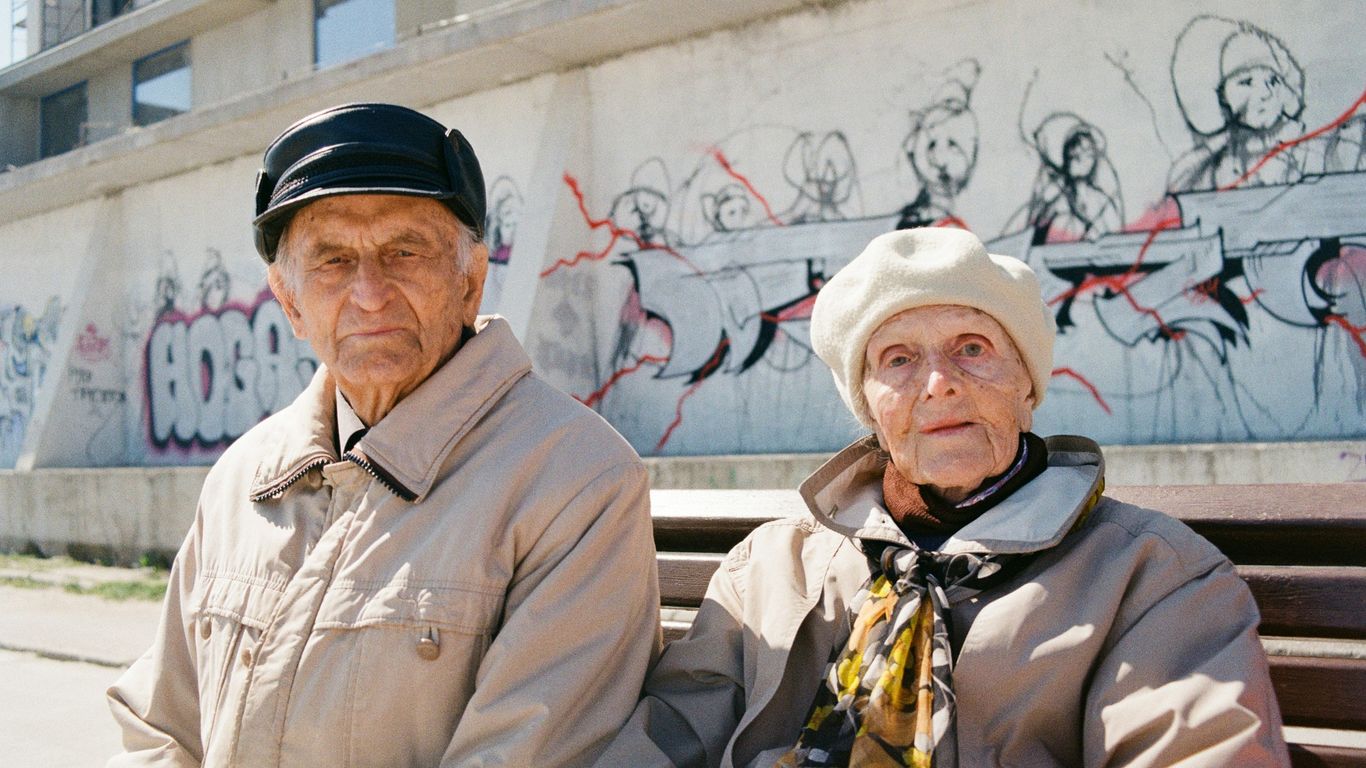 a man and woman standing in front of a wall with graffiti