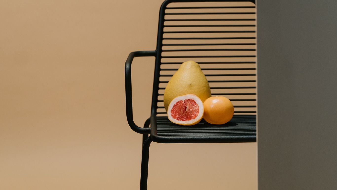 Fruits on a black chair, minimal background, partially obscured view.