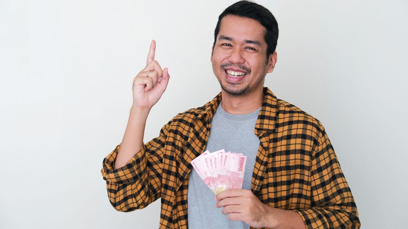 a man holding a bunch of cash and a peace sign