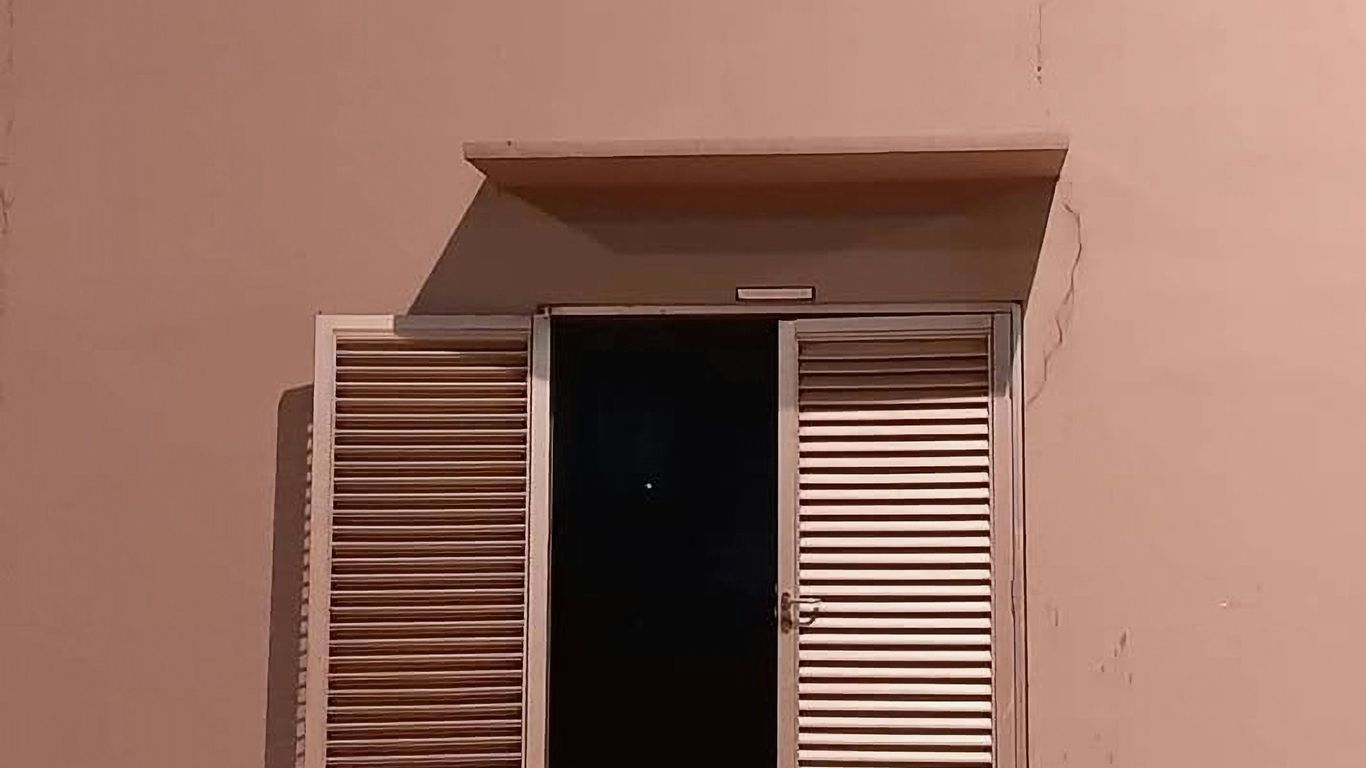 A room with a door and a window with shutters