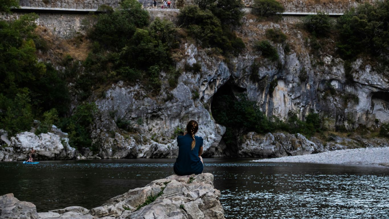 a man standing on a rock by a body of water