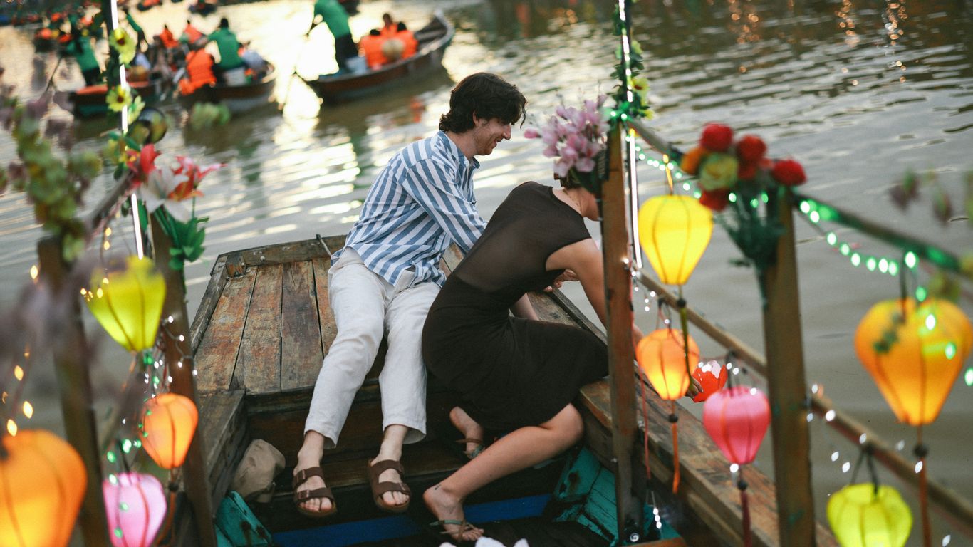 People board a decorated boat on a river.