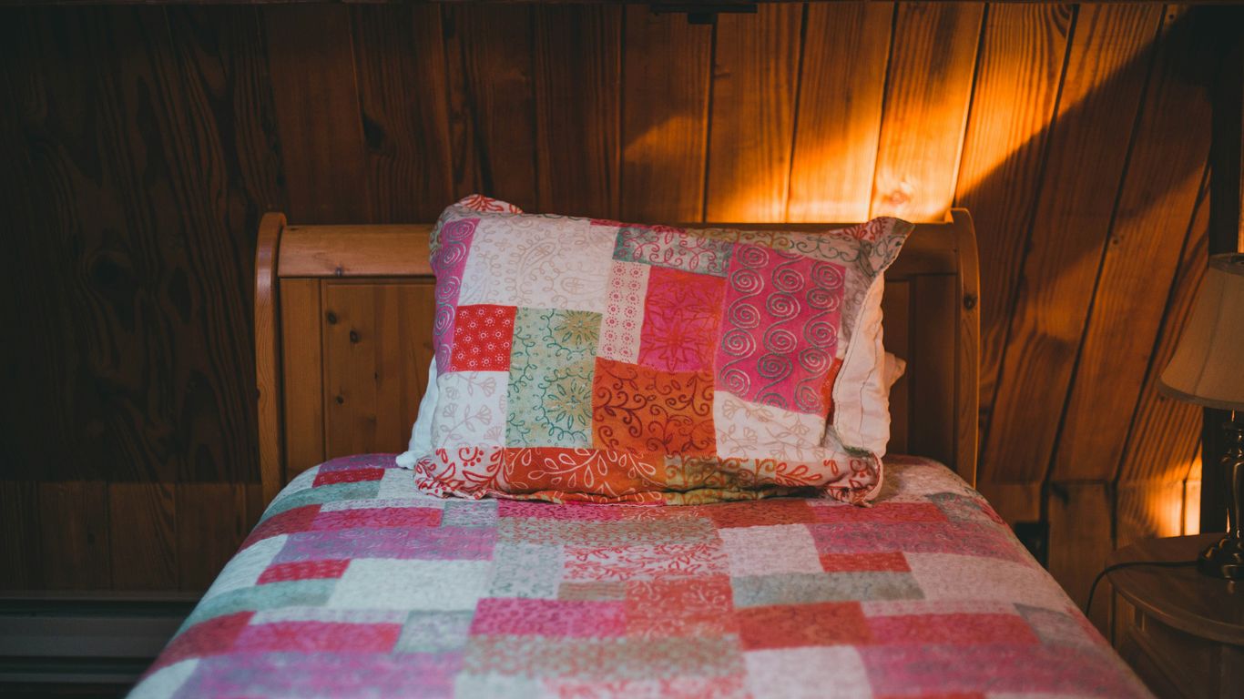 a bed with a colorful quilt on top of it