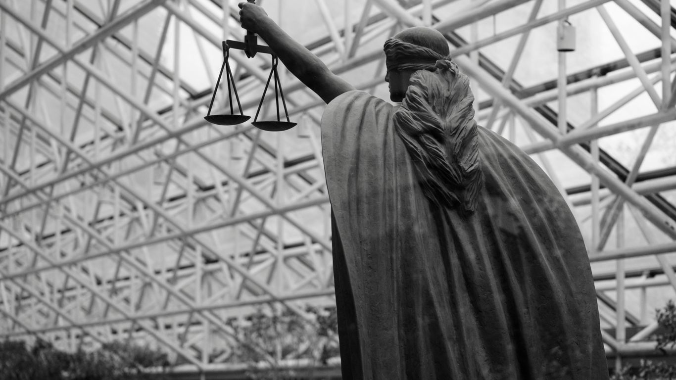 Statue of lady justice holding scales indoors
