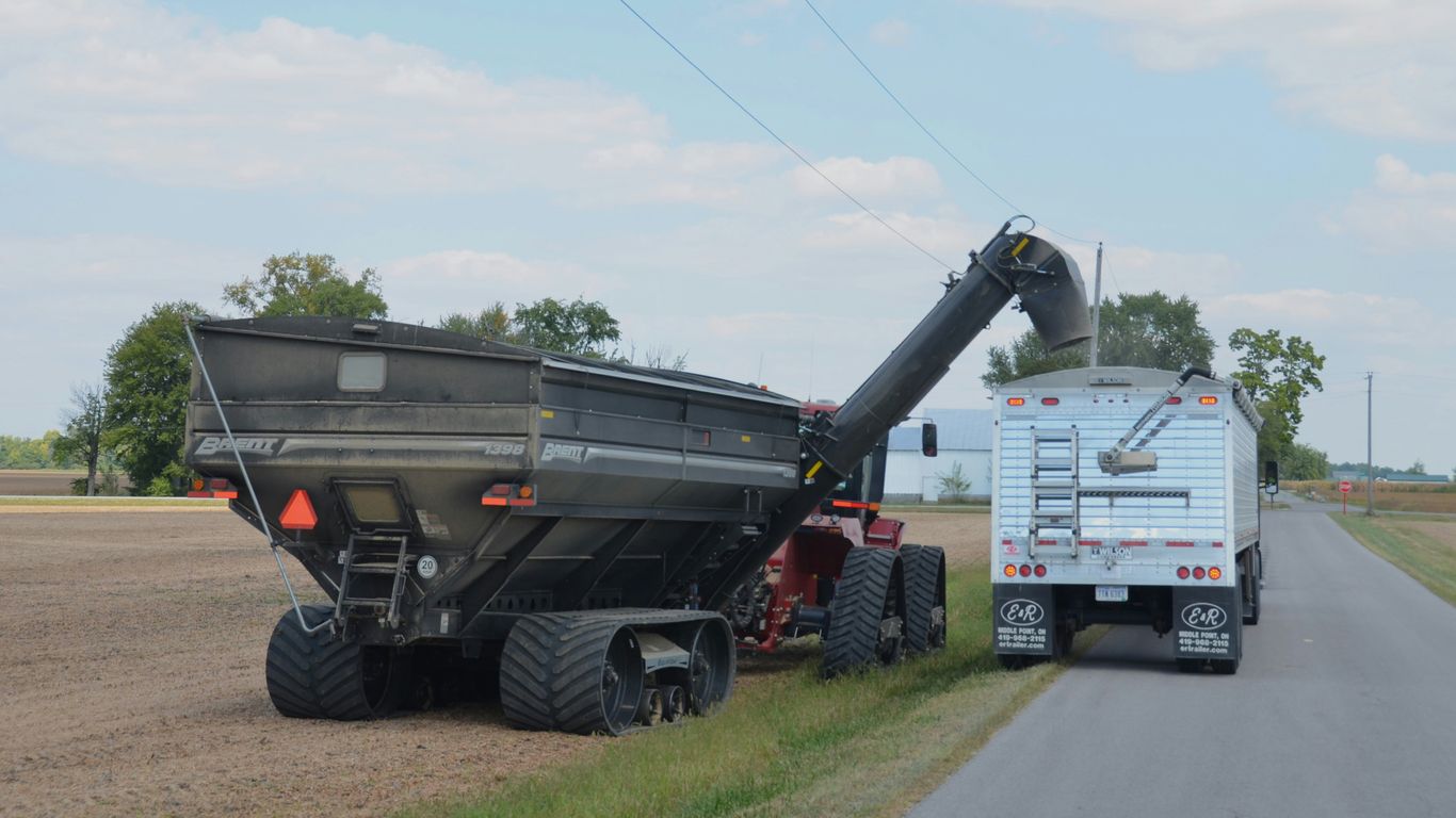 Tractor and trailer unloading grain on a rural road.