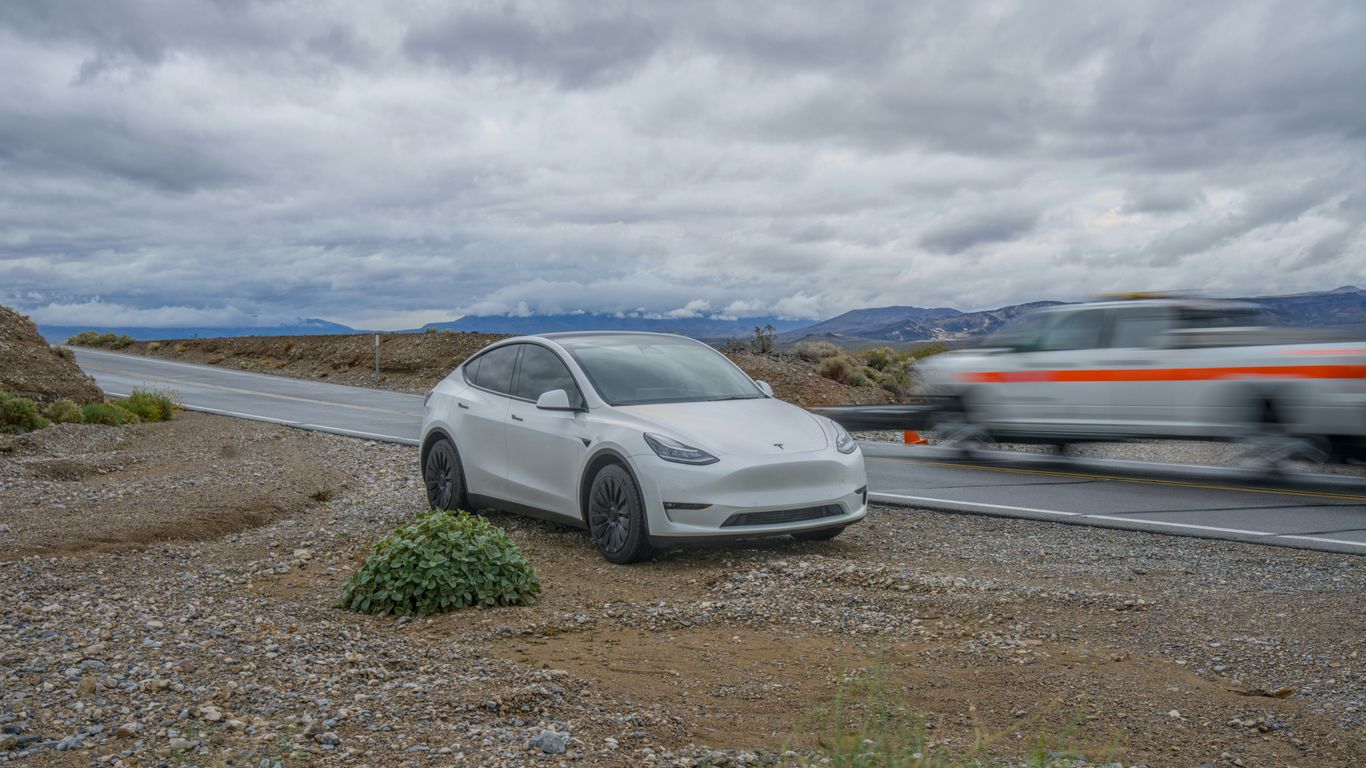 White car parked on a gravel roadside under cloudy sky.
