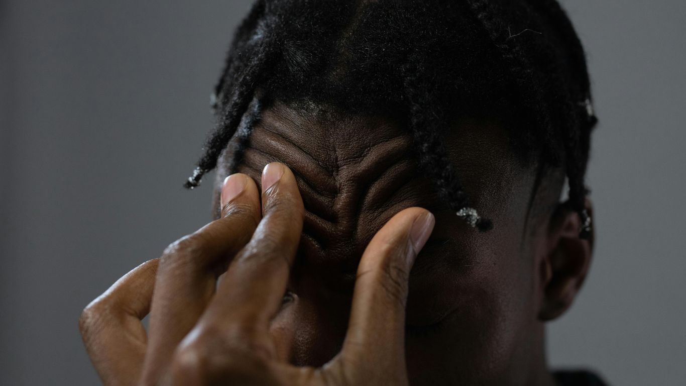 Close-up of a person touching their forehead with their fingers.